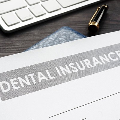 Close-up of dental insurance form close to computer keyboard and cash