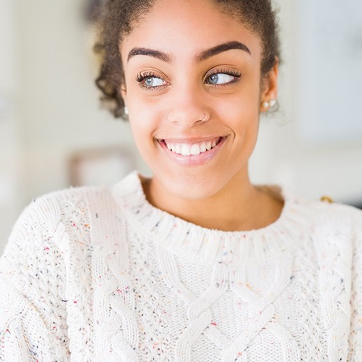 Woman in white sweater standing at home and smiling