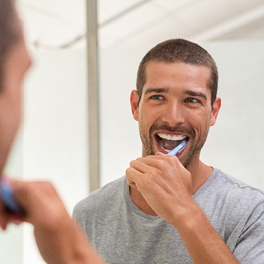 Man looking in mirror and brushing his teeth